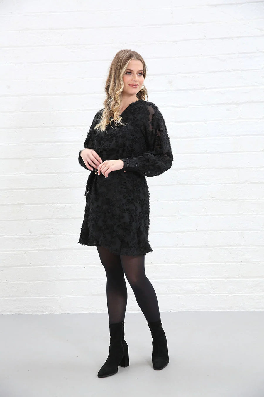 Rant & Rave Susannah Wrap Dress in black worn by a model, front view with textured floral fabric and long sleeves