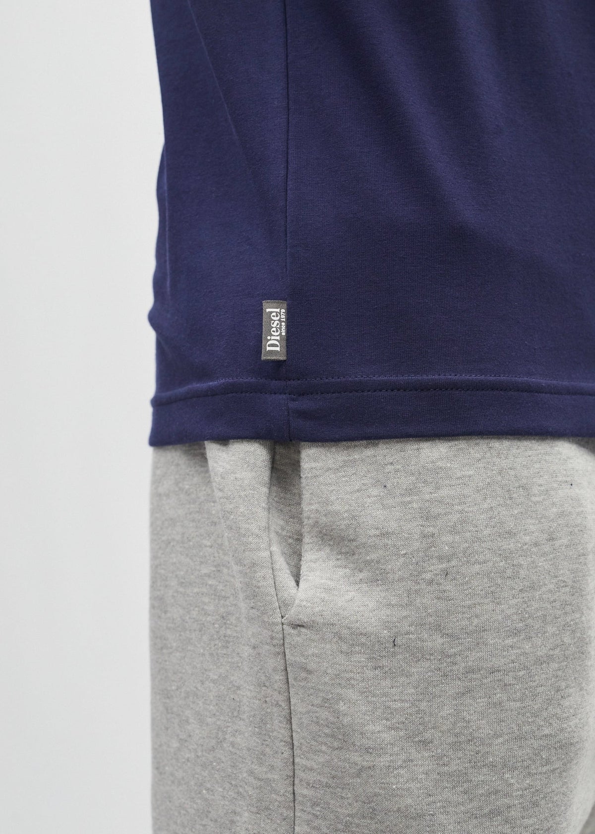 Detail view of the Diesel Walter Tee in navy showing the woven Diesel logo tag at the hem.