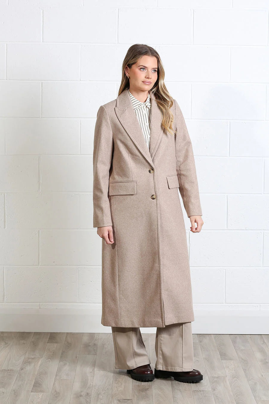 Rant & Rave Olivia Coat in biscuit, three - quarter front view worn by a model with a striped shirt and wide - leg trousers