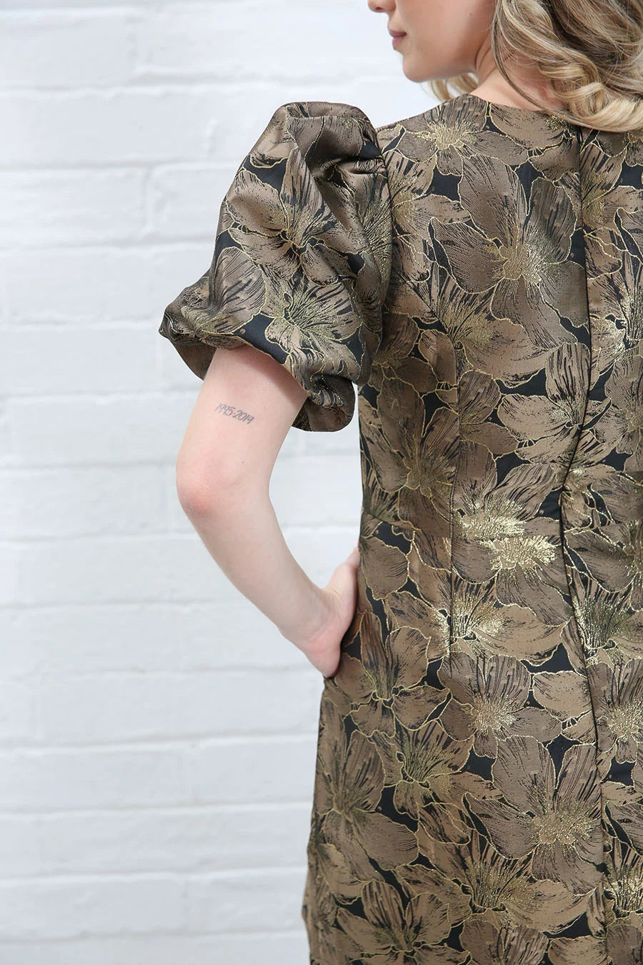 Rant & Rave Evelyn Dress in black and gold floral jacquard, back detail view showing puff sleeve, back seam and floral pattern.