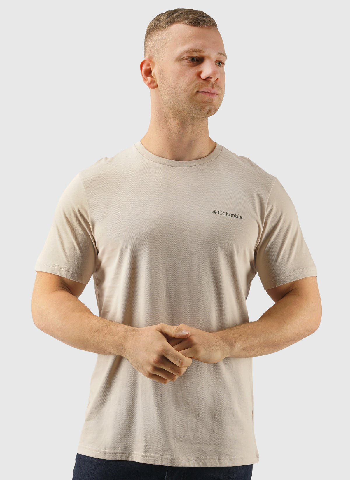 Man wearing a beige t-shirt with Columbia logo on a light gray background