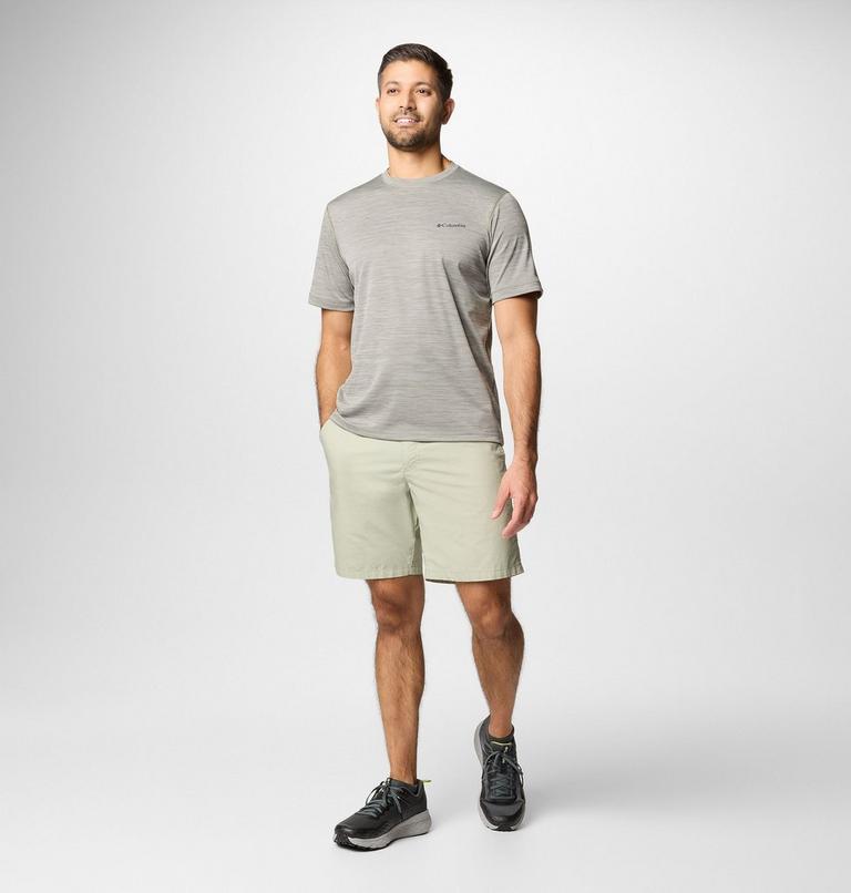 Man wearing a gray t-shirt and beige shorts on a white background