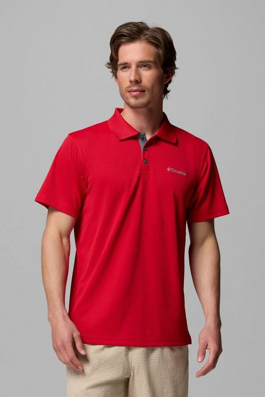 Man wearing a red polo shirt with a brand logo on a gray background