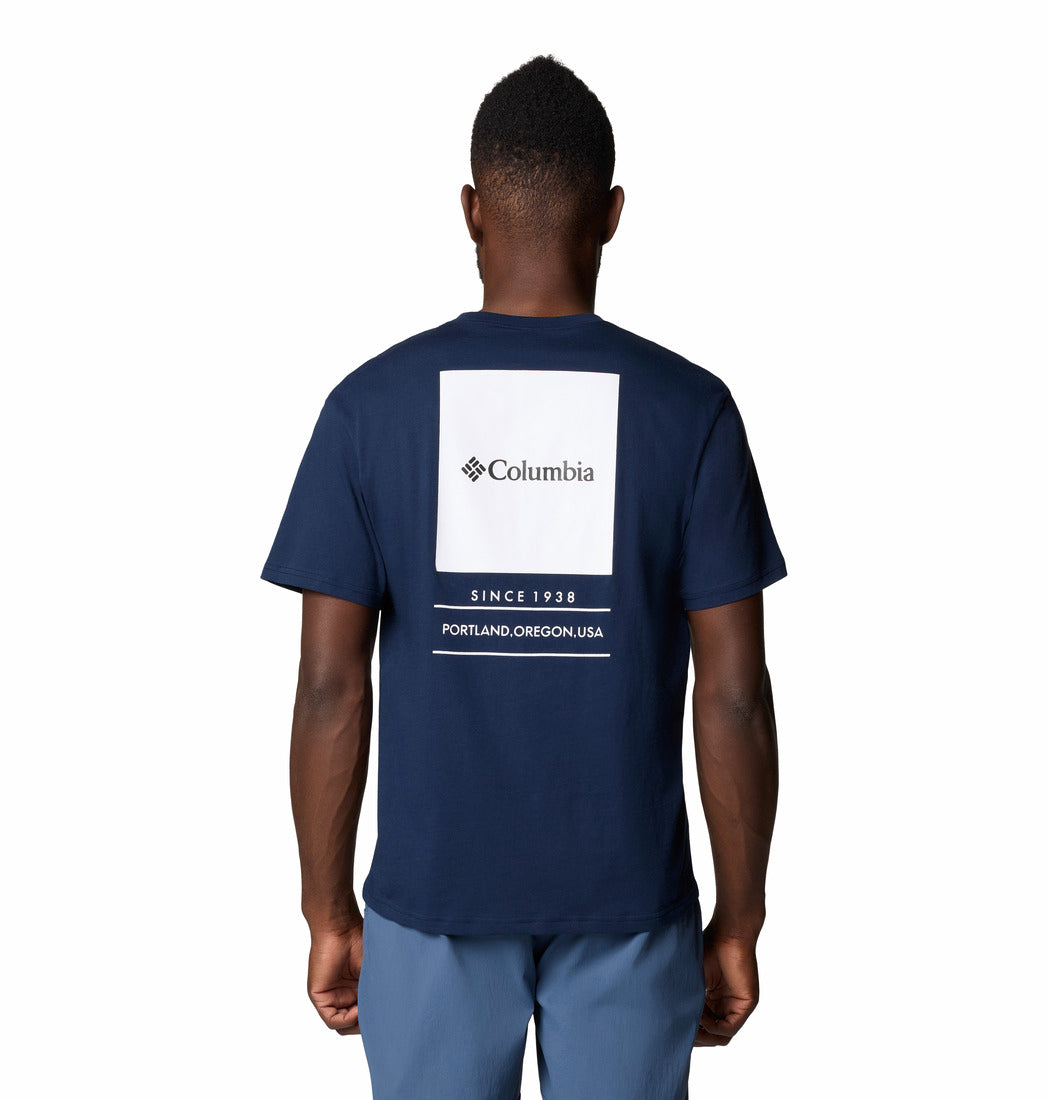 Person wearing a navy blue t-shirt with Columbia logo on the back, standing against a white background