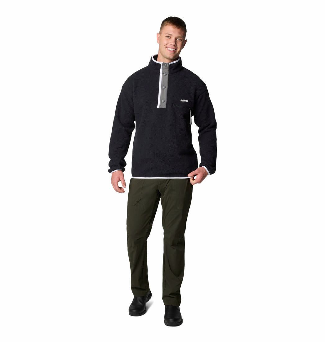 Man wearing a black pullover with a gray zipper and green pants on a white background