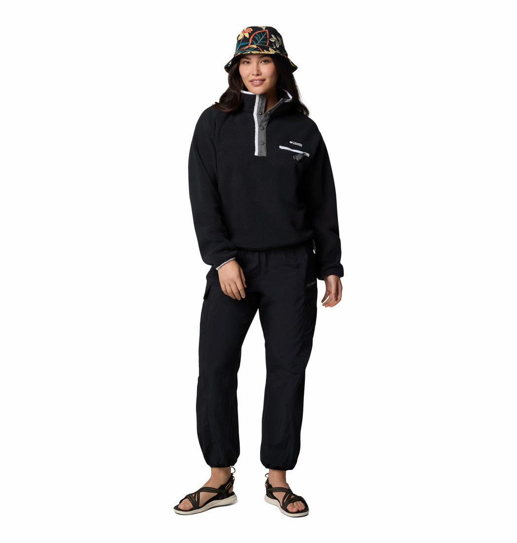 Person wearing a black outfit with a hood and colorful bucket hat on a white background