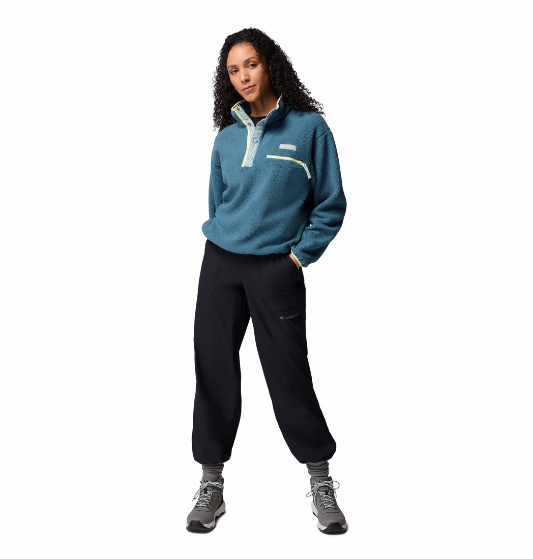 Person wearing a teal fleece pullover and black pants on a white background