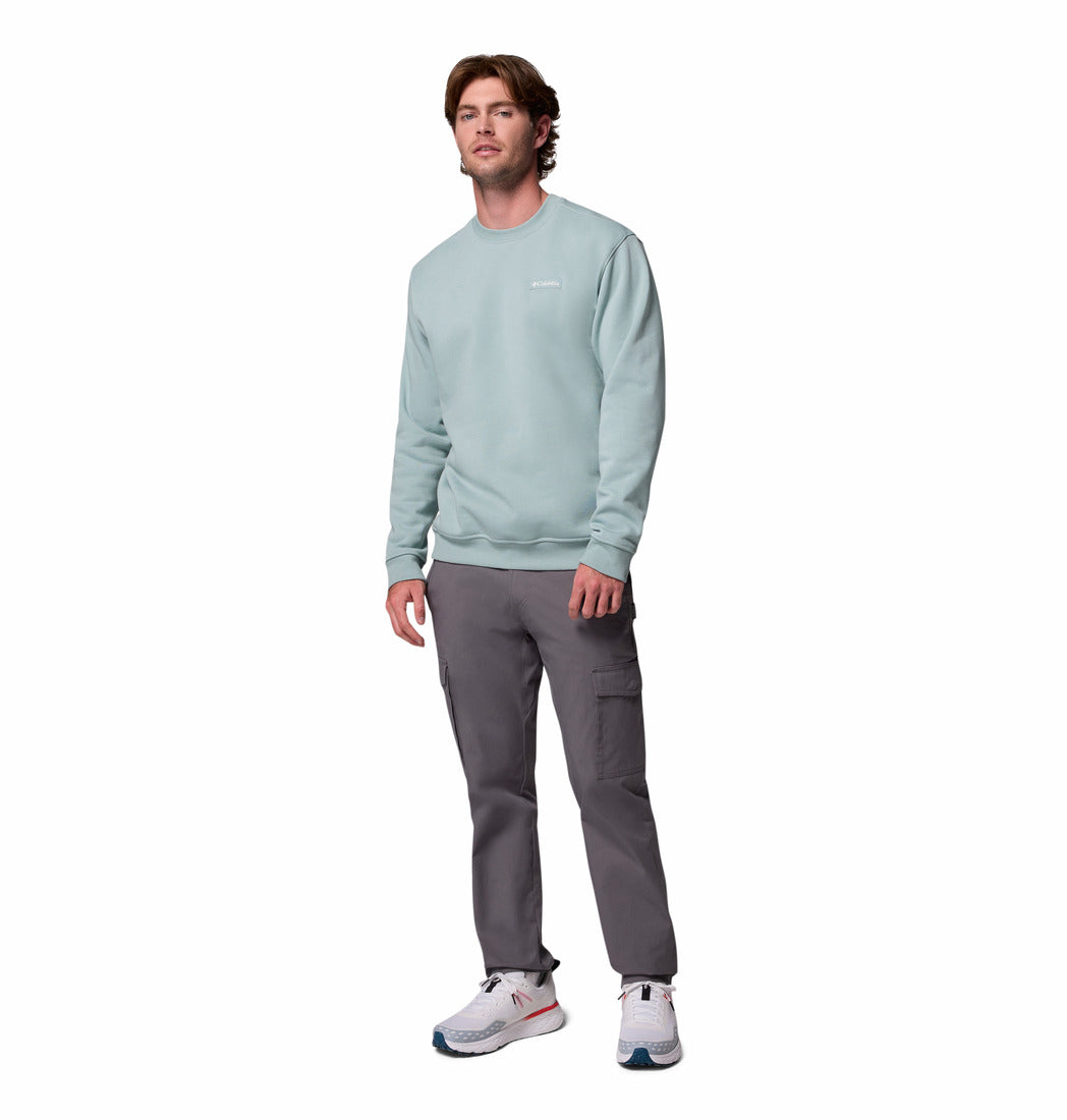 Man wearing a light green sweatshirt and gray pants on a white background