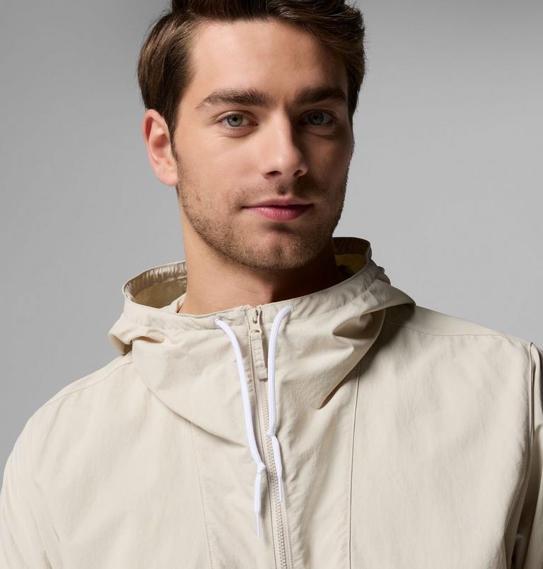 Man wearing a beige hooded jacket against a gray background