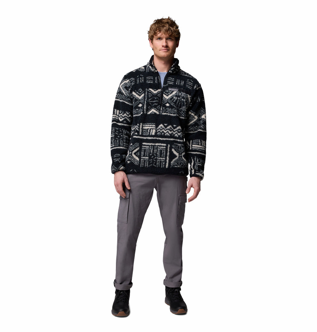 Person wearing a patterned black and white jacket with gray pants on a white background