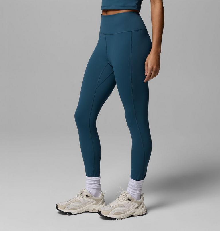 Person wearing teal leggings and white sneakers on a gray background