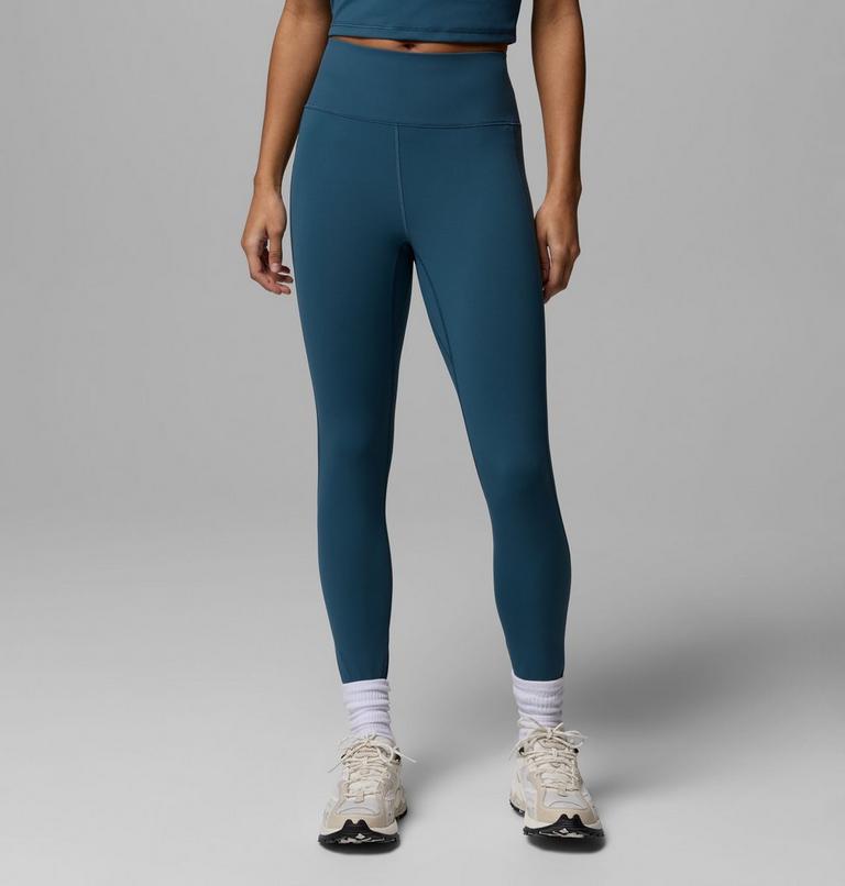 Person wearing teal leggings and white sneakers on a gray background