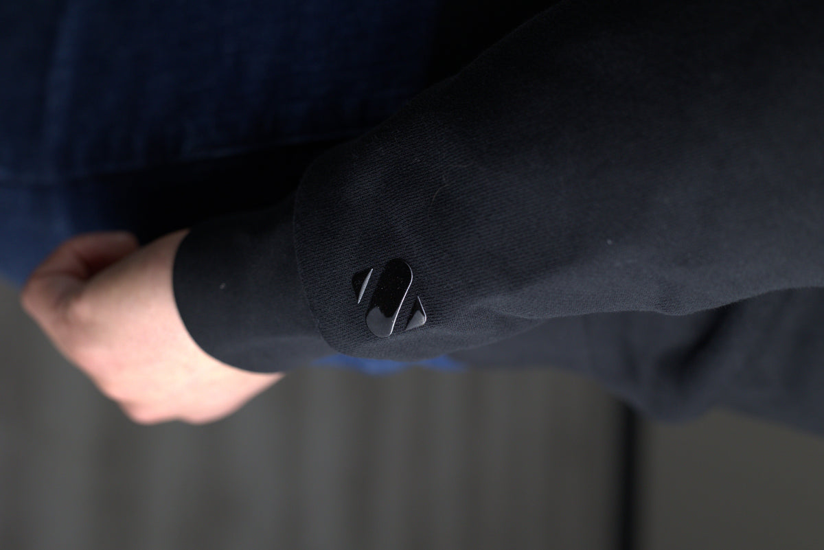 Close-up of the tonal logo on the Element black sweatshirt cuff worn on wrist