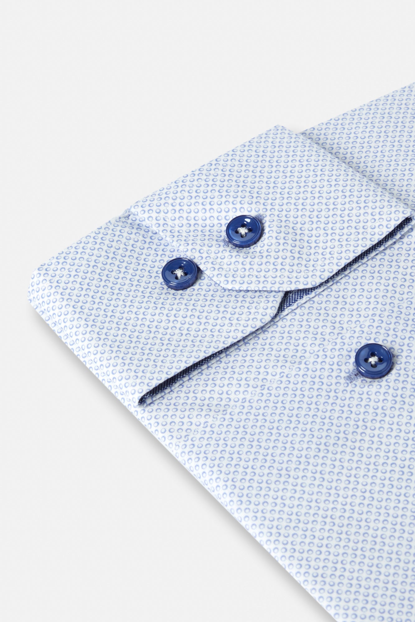 Close-up of a light blue textured shirt with dark blue buttons on a white background