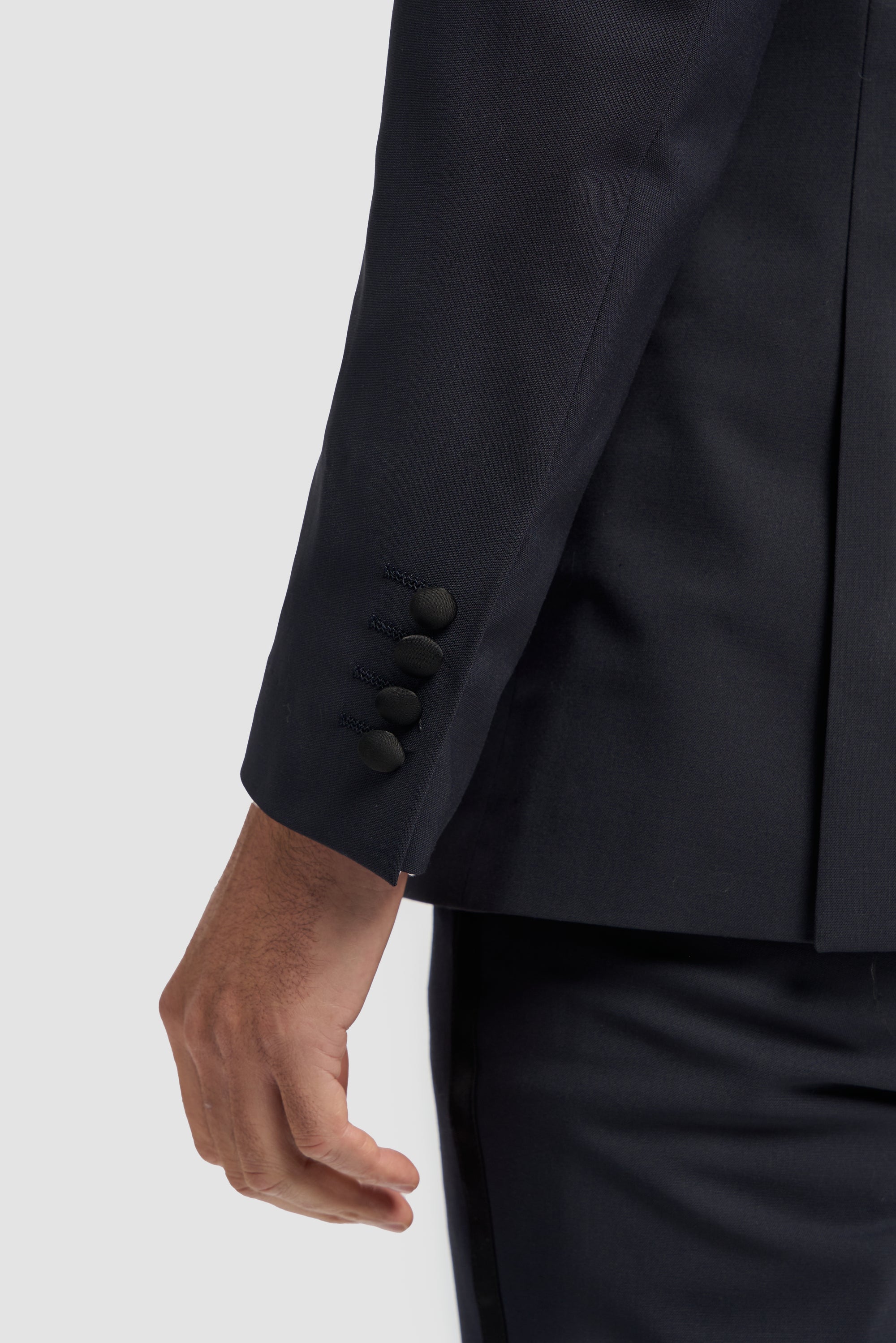 Close-up of a dark navy suit jacket with buttons on a light gray background