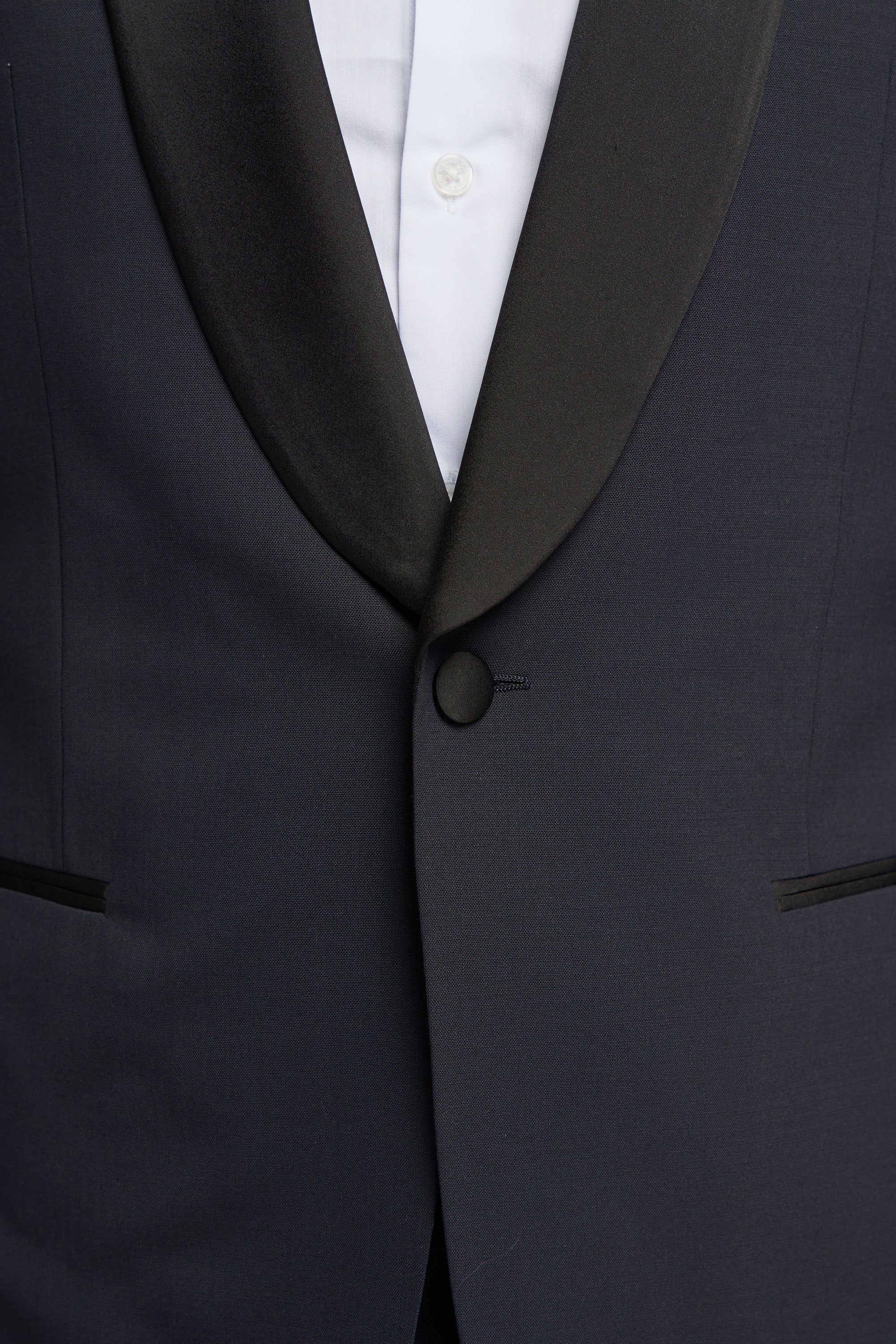 Close-up of a dark navy tuxedo jacket with a white shirt underneath.