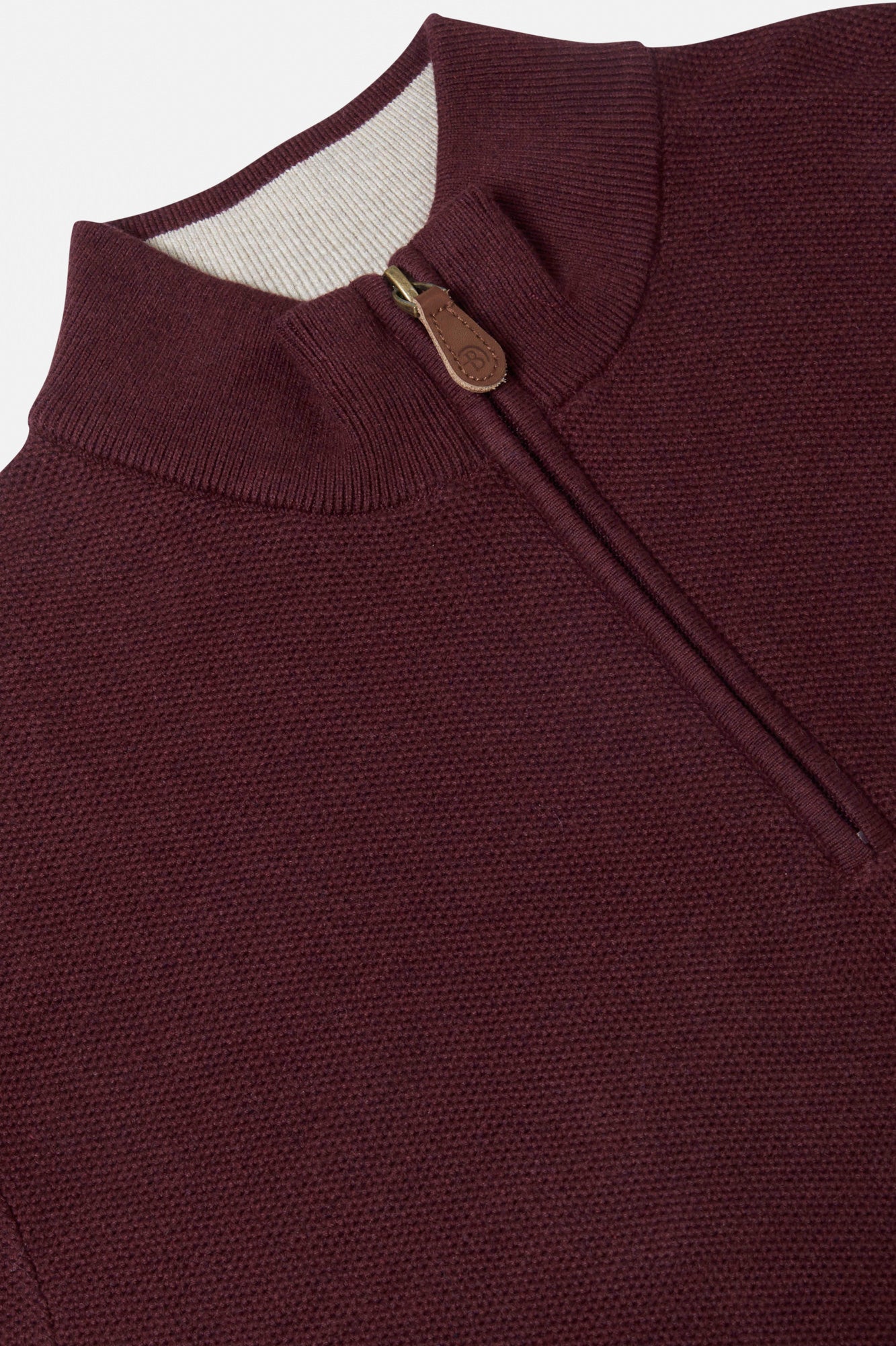 Close-up of a maroon sweater with a zipper and button detail on a white background