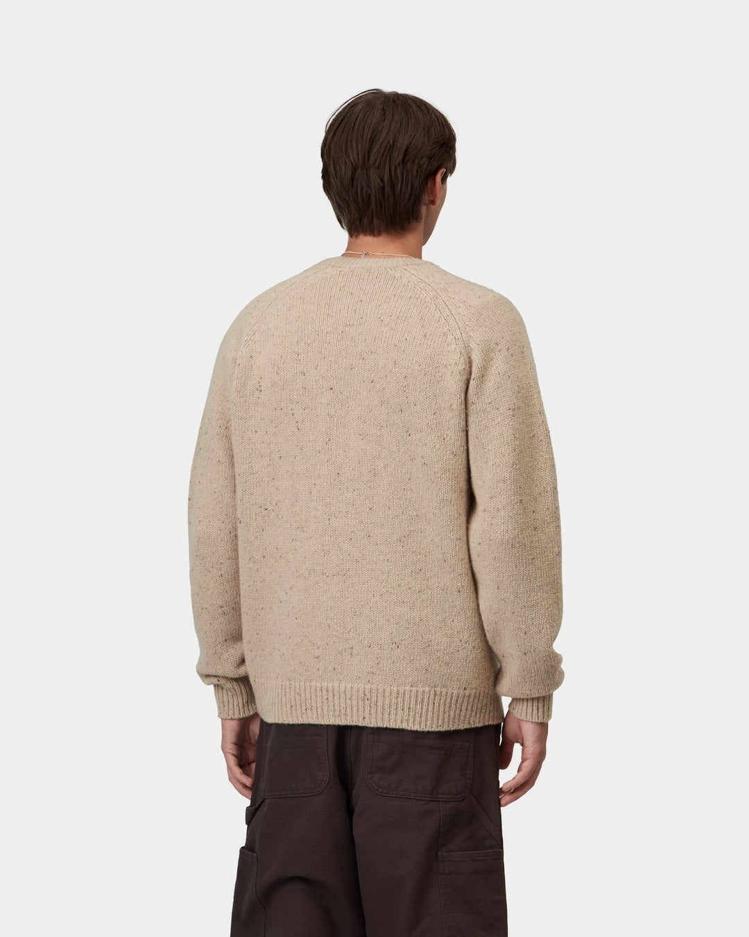 Back view of a Carhartt WIP Anglistic Sweater in Speckled Fleur de Sel, showing the knit texture and ribbed cuffs and hem, shown on model.