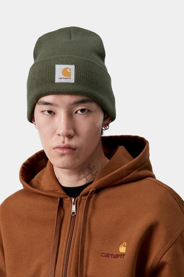 Person wearing a green beanie and brown hoodie with Carhartt logo on a white background