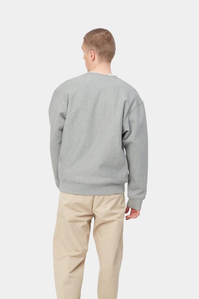 Man wearing a gray sweater and beige pants on a white background