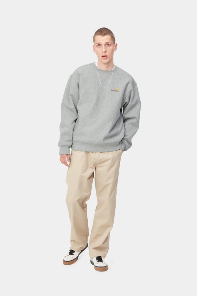 Man wearing a gray sweatshirt and beige pants on a white background