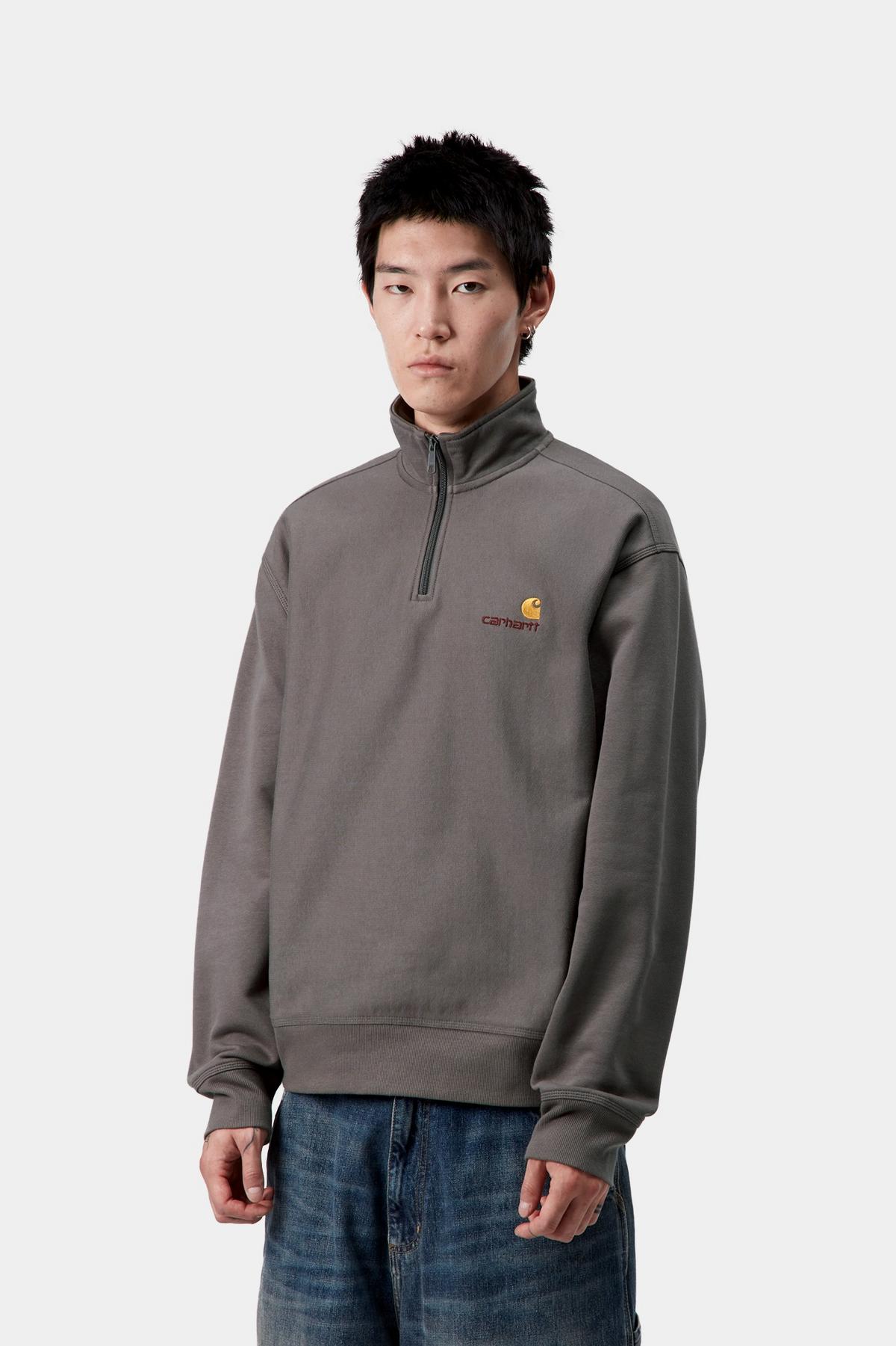 Man wearing a gray pullover with a logo on a white background