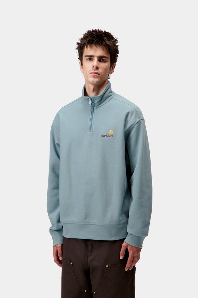 Man wearing a light blue pullover with a logo on a white background