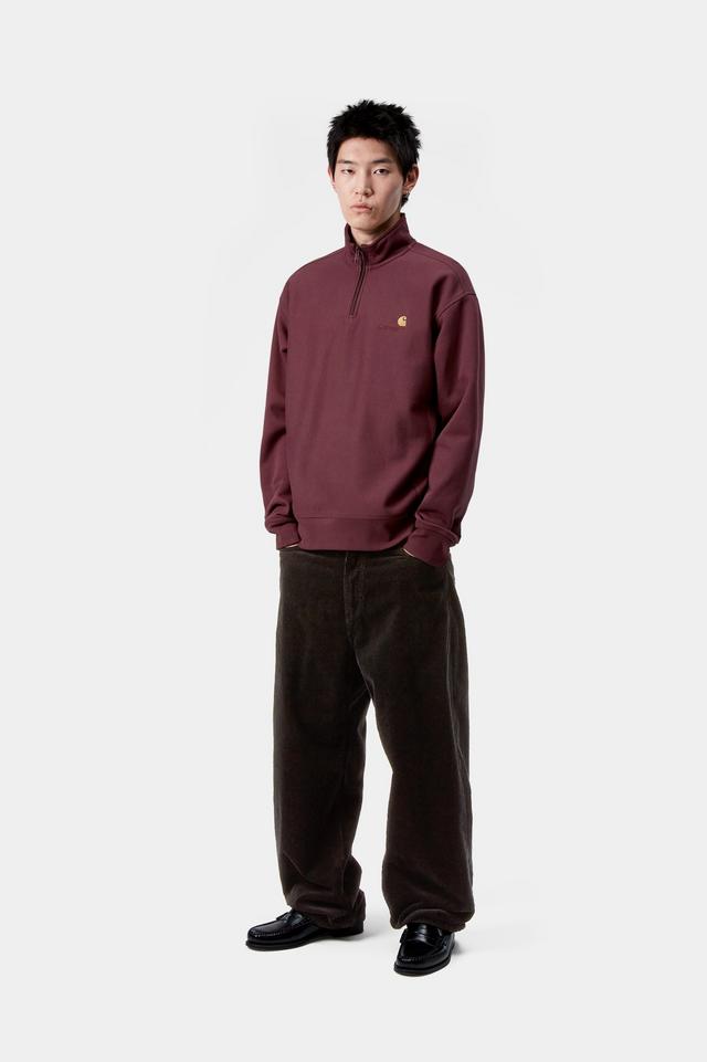 Person wearing a burgundy half-zip sweatshirt and brown pants on a white background