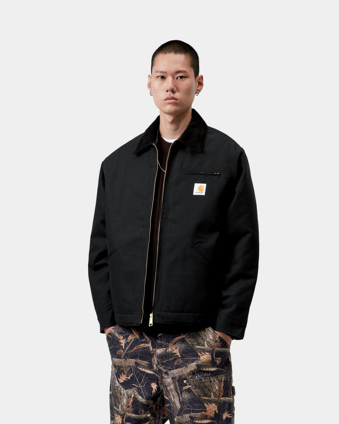 Carhartt WIP OG Detroit Jacket in Black / Black, shown front view with a black corduroy collar, zip front, chest pocket, and small logo patch, shown on model.