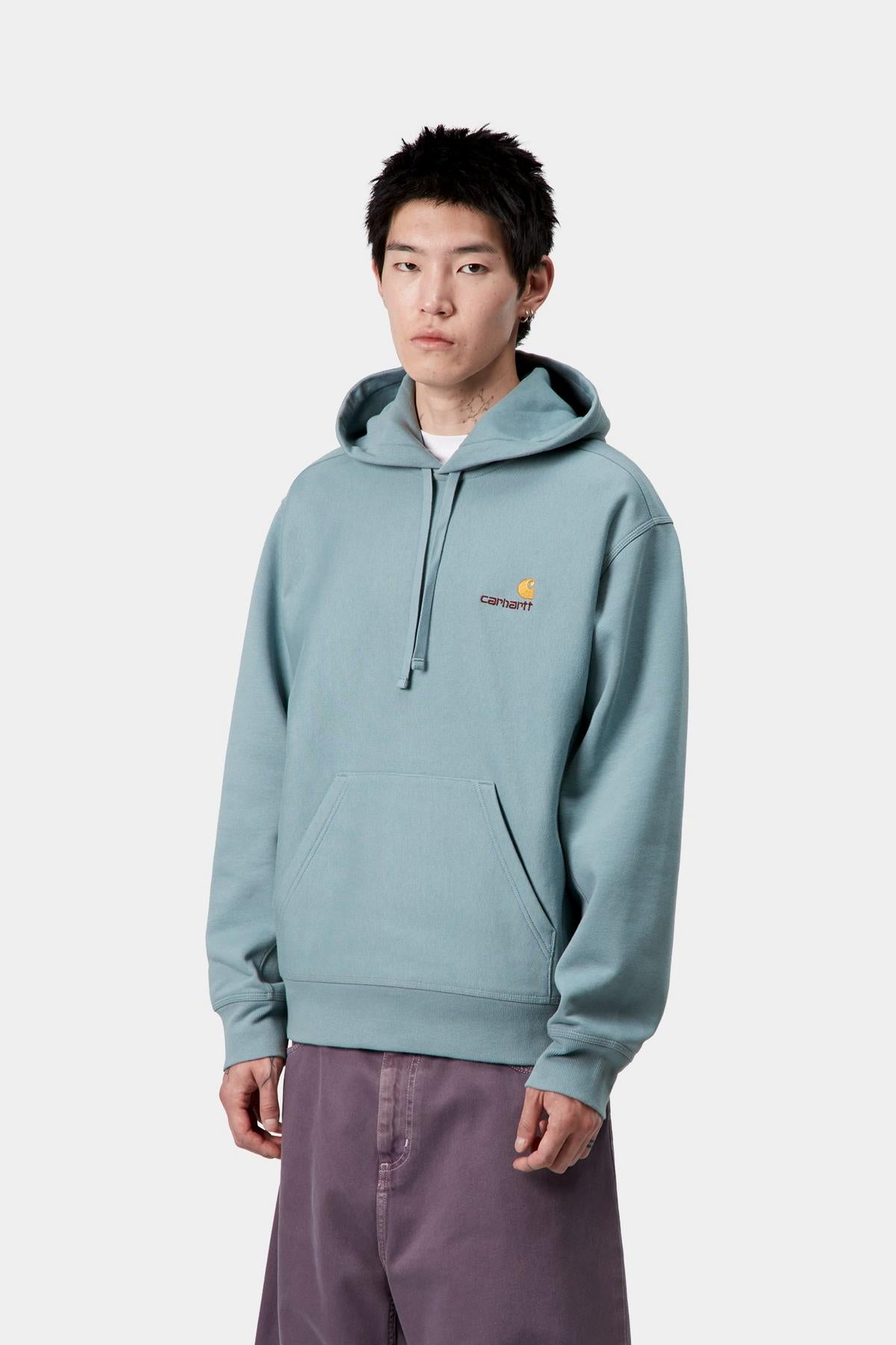 Person wearing a light blue hoodie with Carhartt logo on a white background