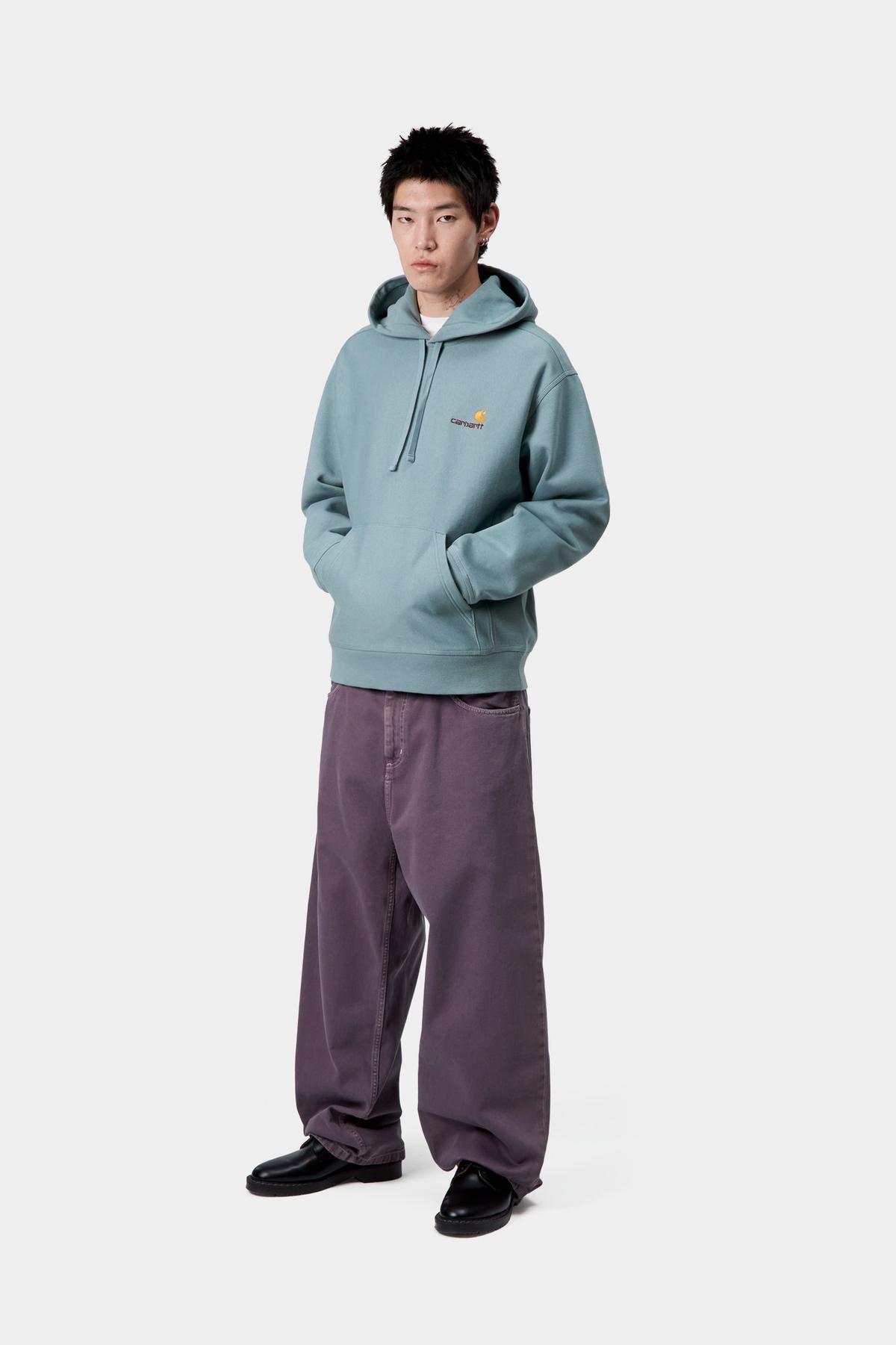 Person wearing a light blue hoodie and purple pants on a white background