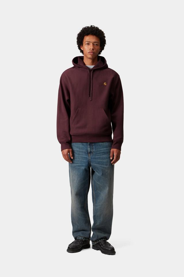 Person wearing a maroon hoodie with a logo and blue jeans on a white background