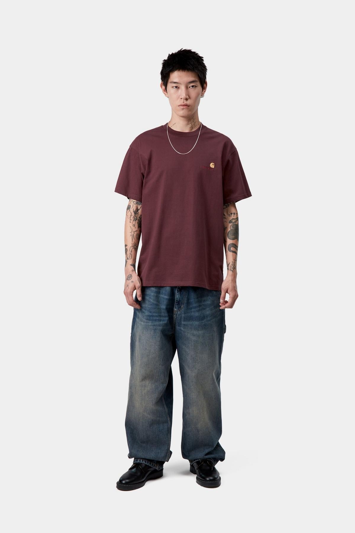 Person wearing a maroon t-shirt and blue jeans on a white background