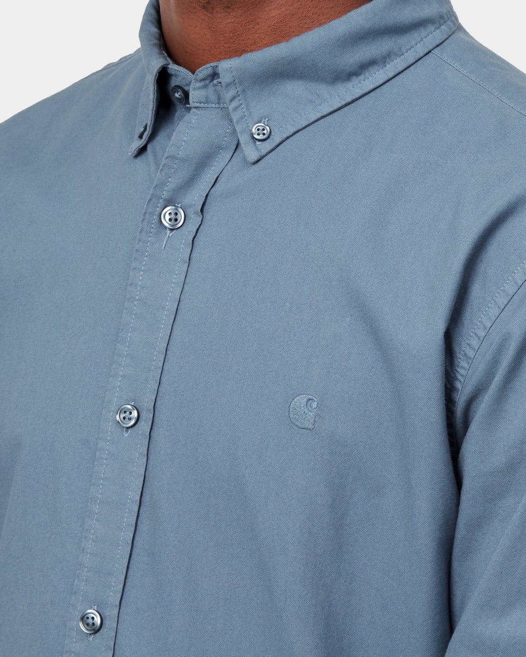 Close-up of the Carhartt WIP L/S Bolton Shirt in Icesheet, showing the button-down collar, front buttons, and embroidered chest logo, shown on model.