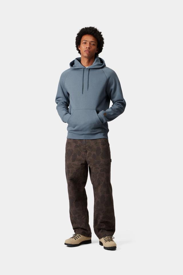 Person wearing a blue hoodie and patterned pants on a white background
