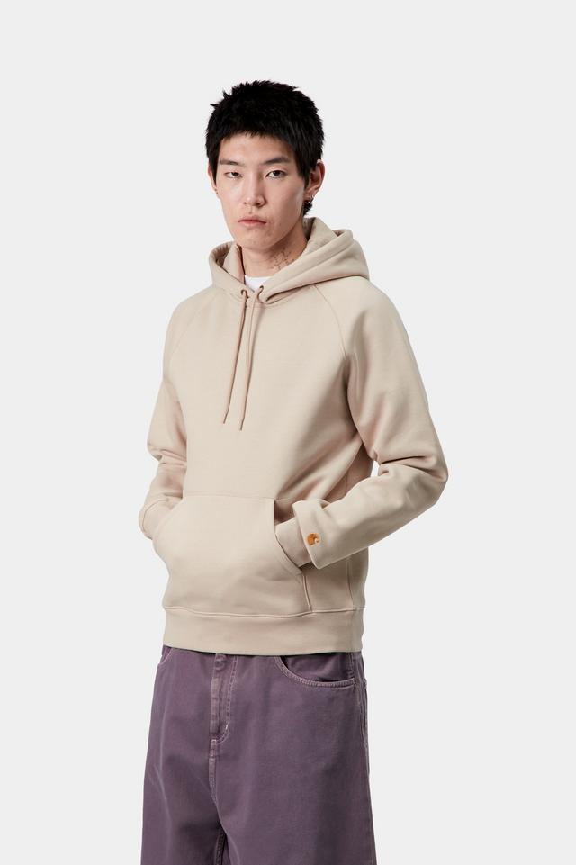 Person wearing a beige hoodie and purple pants on a white background