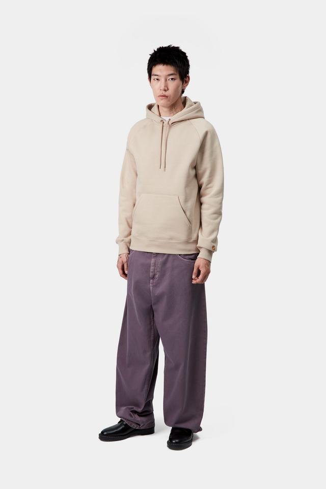 Person wearing a beige hoodie and purple pants on a white background