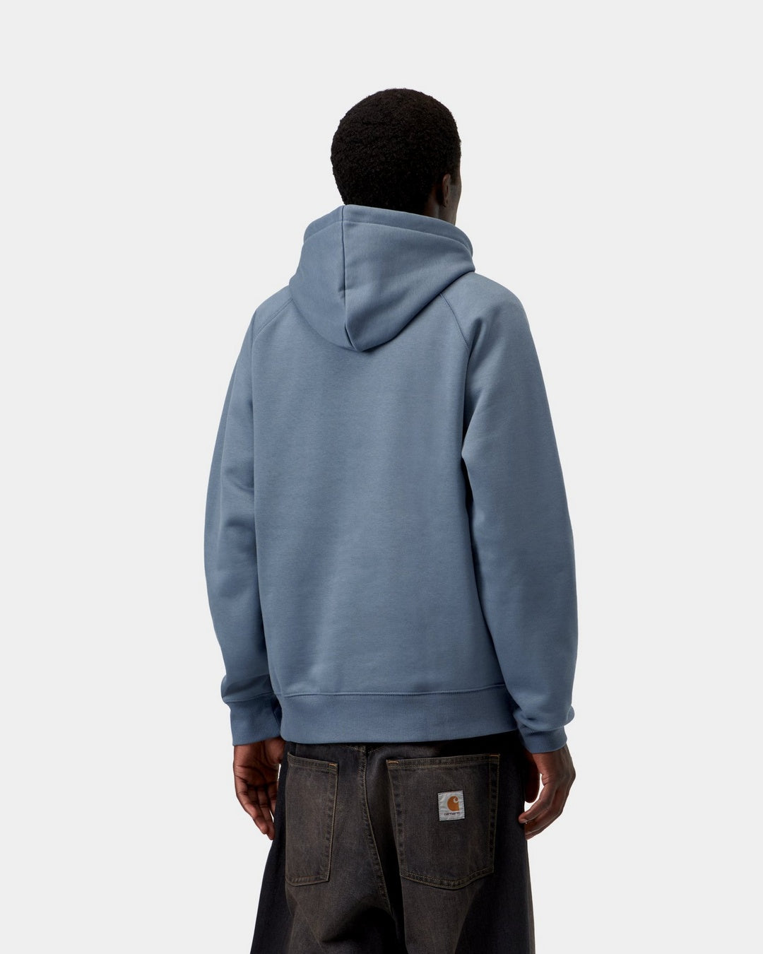 Carhartt WIP Hooded Chase Sweatshirt in Icesheet / Gold, back view, worn by model, with hood up and Carhartt WIP logo patch on the back of the jeans.