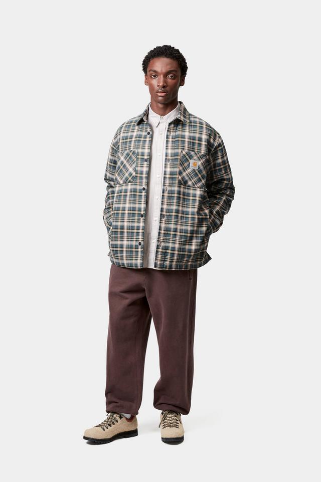 Person wearing a plaid shirt over a white shirt with brown pants on a white background