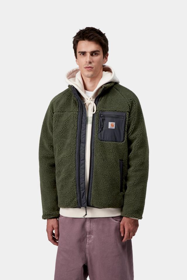 Man wearing a green jacket with a white hoodie underneath on a light gray background