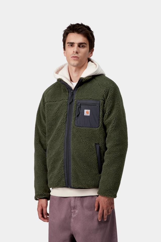 Man wearing a green jacket with a white hoodie underneath on a light gray background