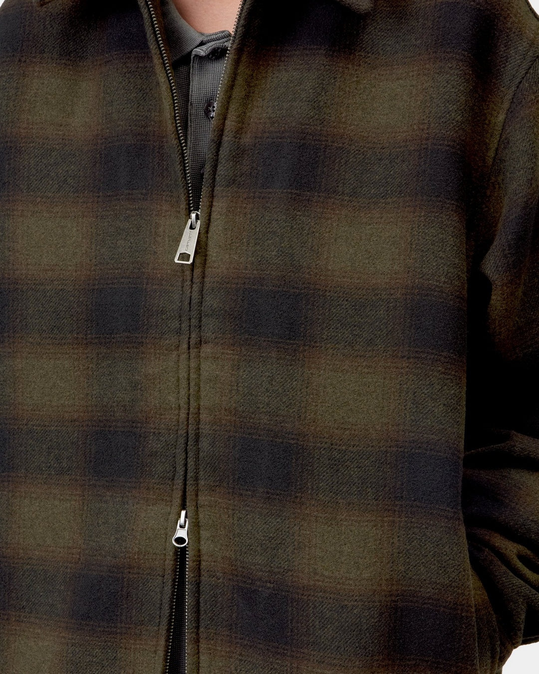 Close-up front view of the Carhartt WIP Alton Jacket in Alton Check, Cypress, showing the zip front closure with silver zipper pulls, the allover check twill fabric, and a collared shirt worn underneath.