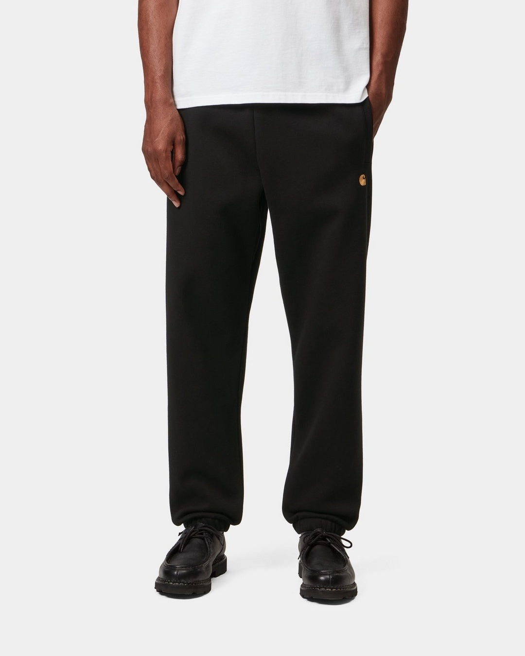 Carhartt WIP Chase Sweat Pant in Black / Gold, front view, with gold C logo on the leg.