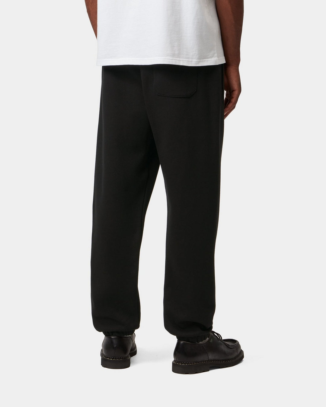 Carhartt WIP Chase Sweat Pant in Black / Gold, rear view, worn with a back pocket visible.