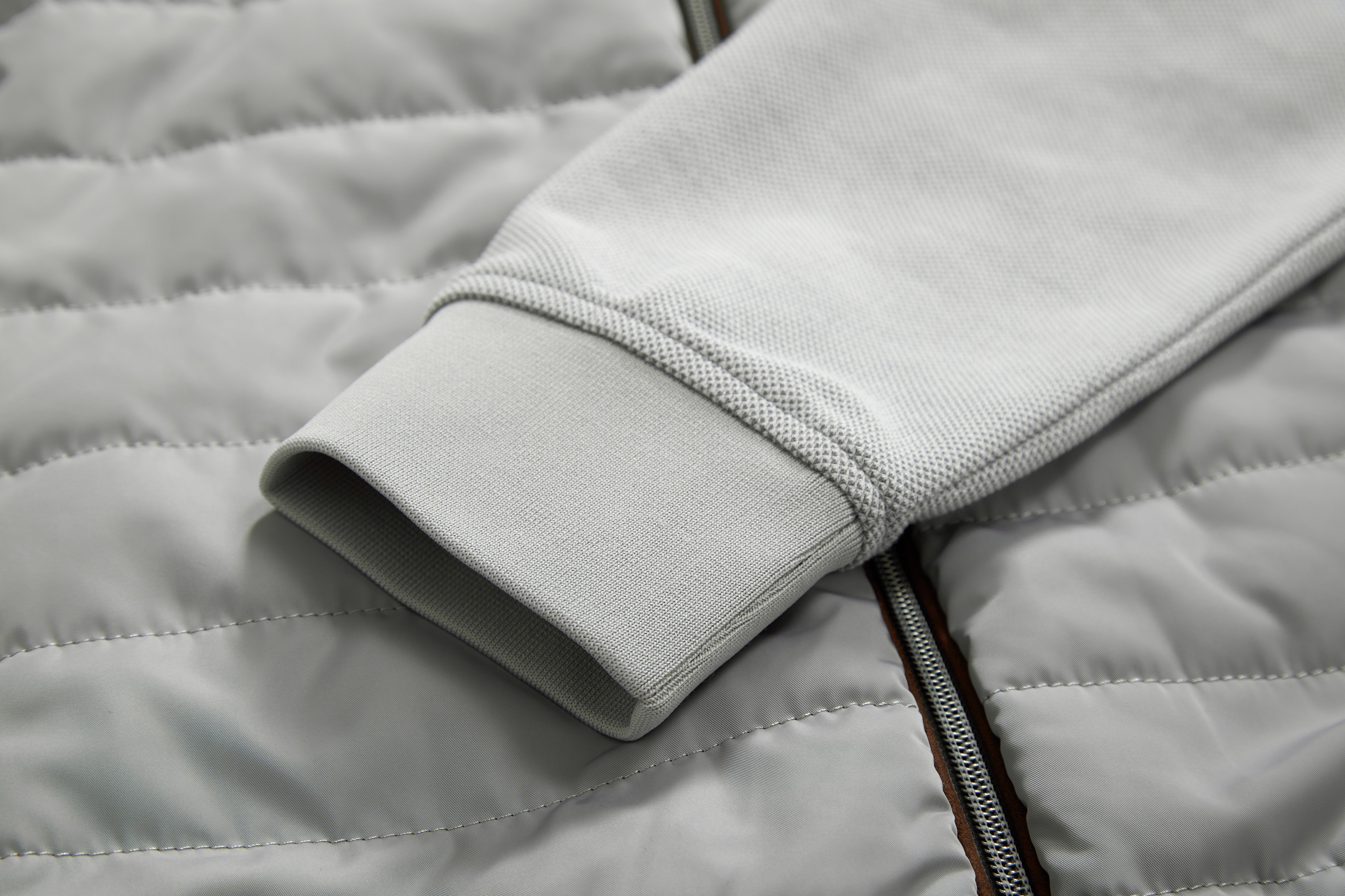 Close-up of a gray quilted jacket with a zipper