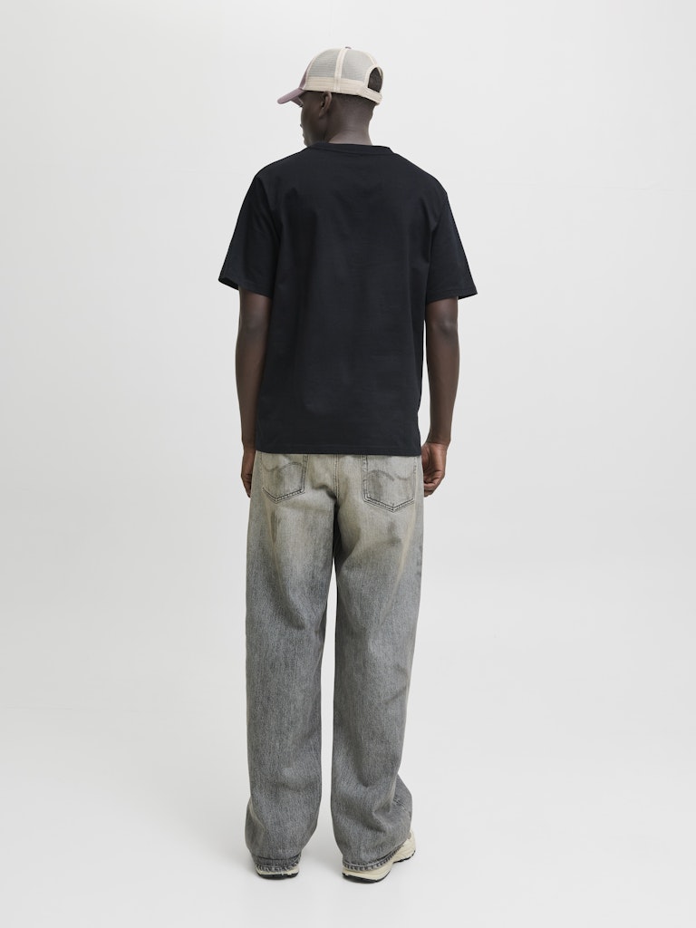 Person wearing a black t-shirt and light blue jeans on a white background