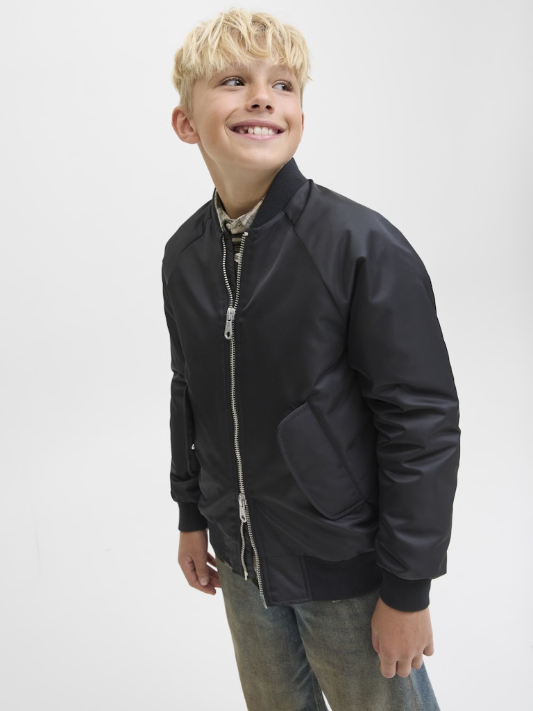 Child wearing a black bomber jacket on a white background