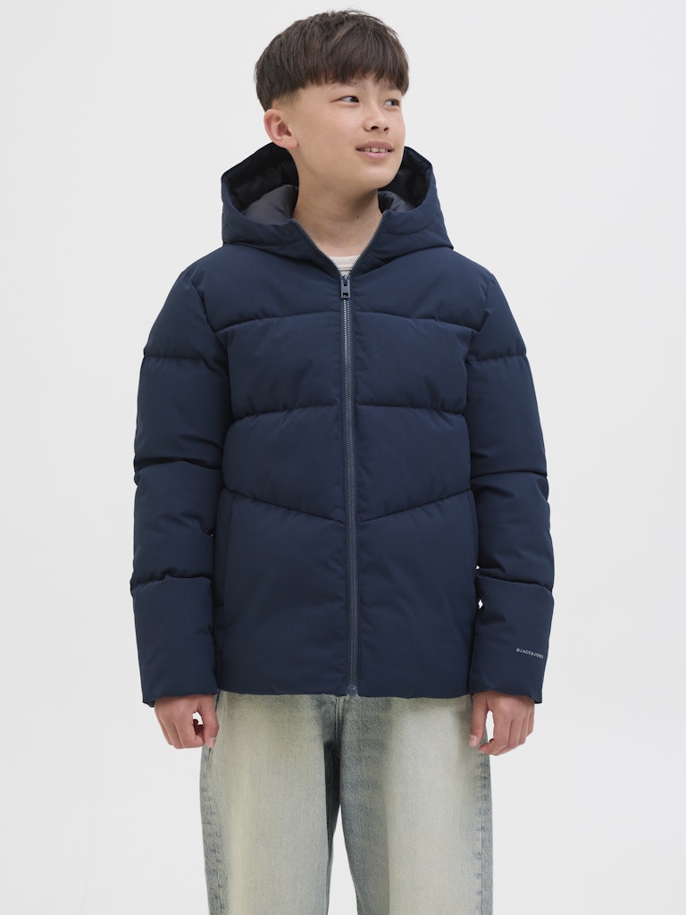 Person wearing a navy blue puffer jacket on a white background