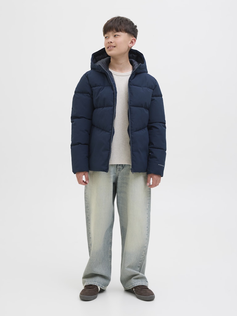 Person wearing a navy puffer jacket on a white background