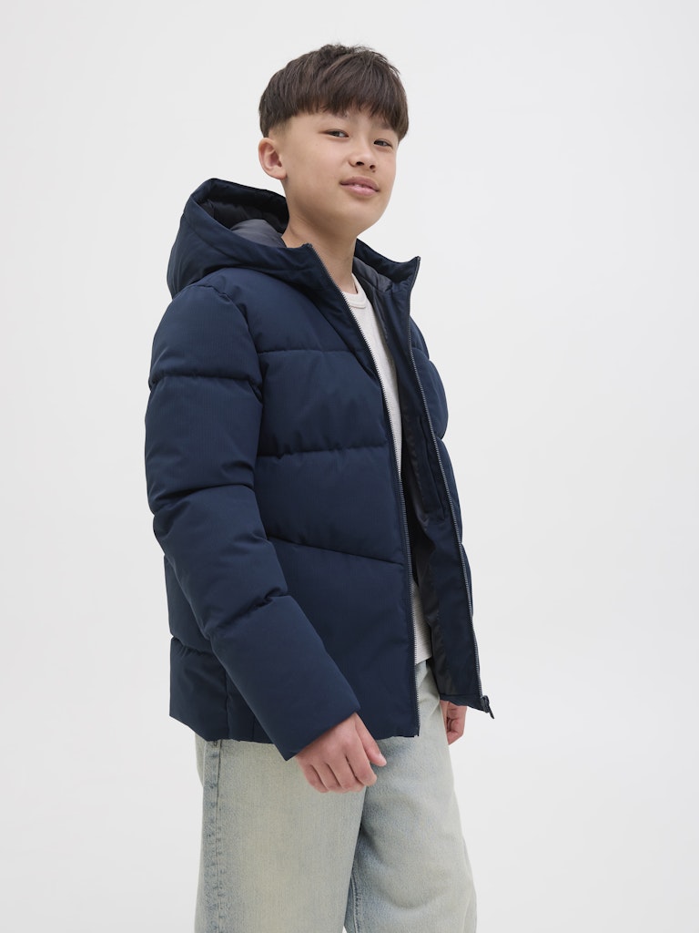 Person wearing a navy blue puffer jacket on a white background
